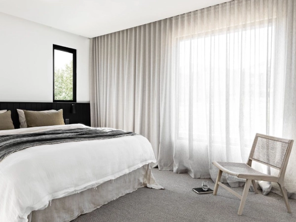 Minimalist-bedroom-with-white-bedding-black-headboard-cane-chair-and-floor-to-ceiling-linen-sheer-curtains